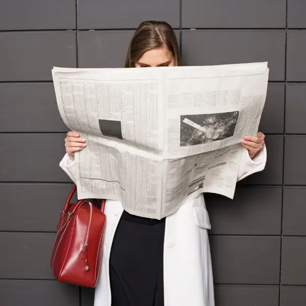 donna legge il giornale su sfondo di piastrelle grige