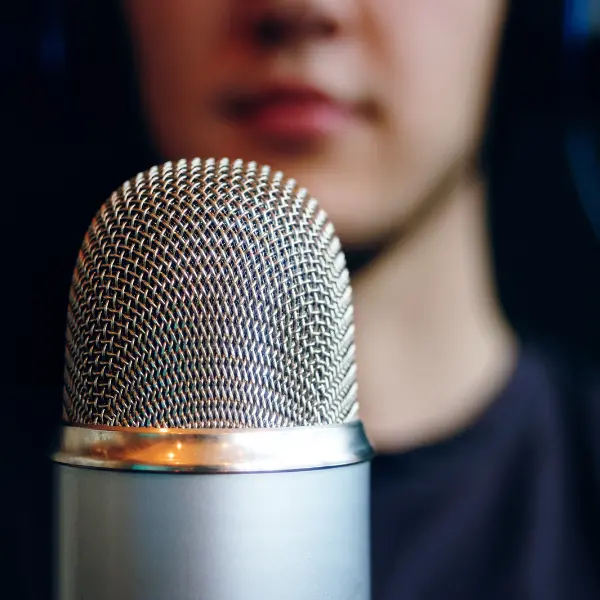 Microfono color acciaio in primo piano e speaker sullo sfondo sfumato