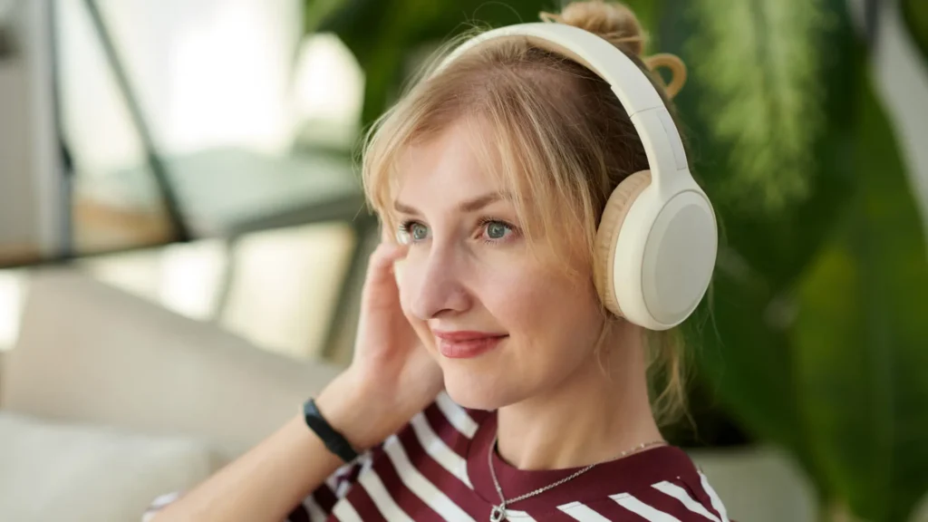 donna bionda com maglie a righe rosse e bianche ascolta un podcast in cuffia