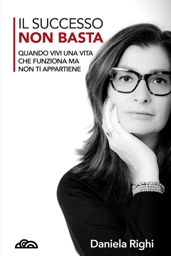 Copertina del libro "Il successo non basta" di Daniela Righi, edito da Poliedricamente Edizioni. L'immagine in bianco e nero mostra un primo piano intenso dell'autrice, una donna con occhiali e capelli scuri che guarda frontalmente l'obiettivo con una mano sotto il mento. In alto a sinistra, il titolo spicca con la parola "NON BASTA" in rosso, seguito dal sottotitolo: "Quando vivi una vita che funziona ma non ti appartiene". In basso a sinistra è presente il logo della casa editrice.